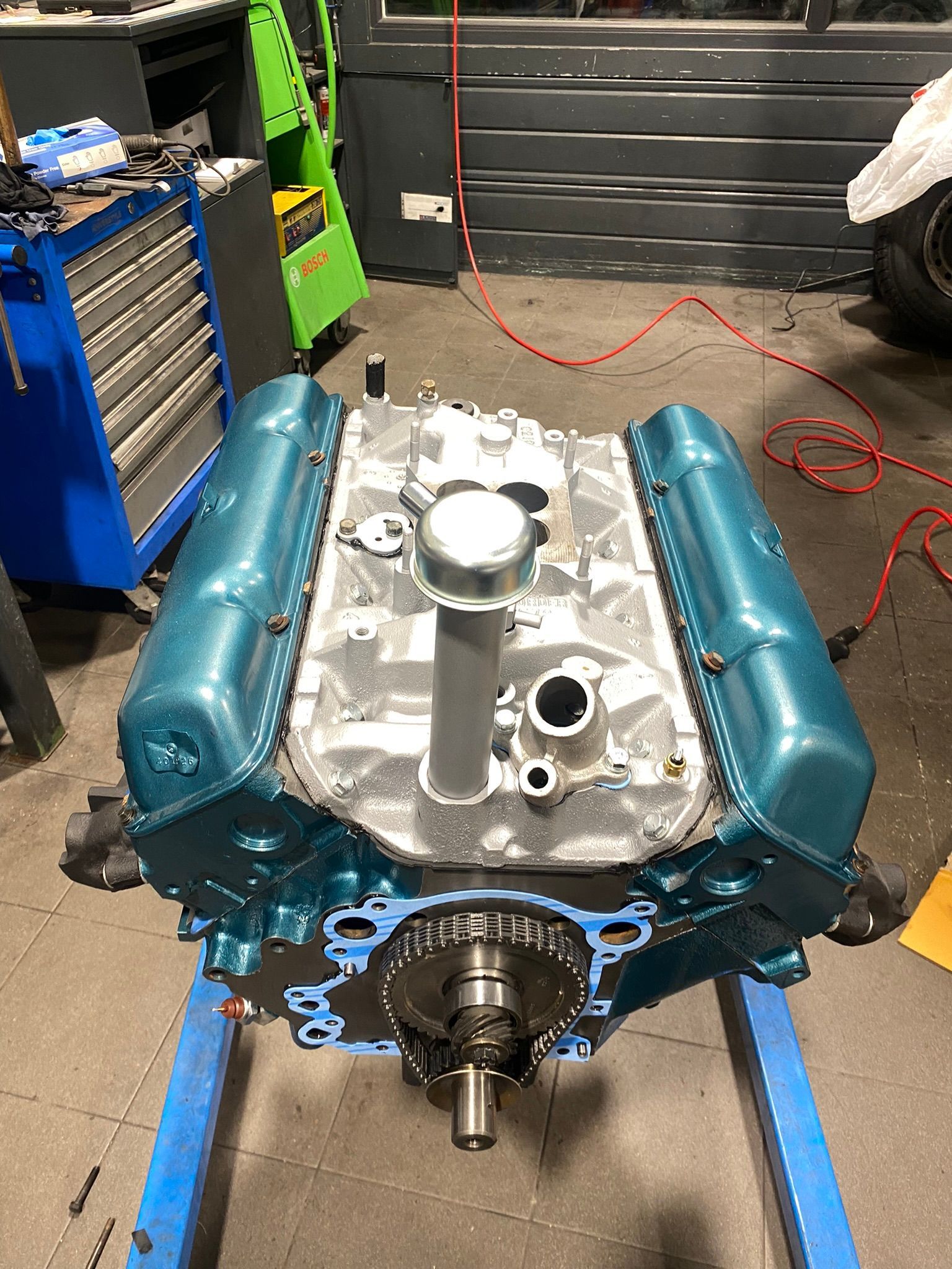 Un moteur bleu est posé sur un support bleu dans un garage.