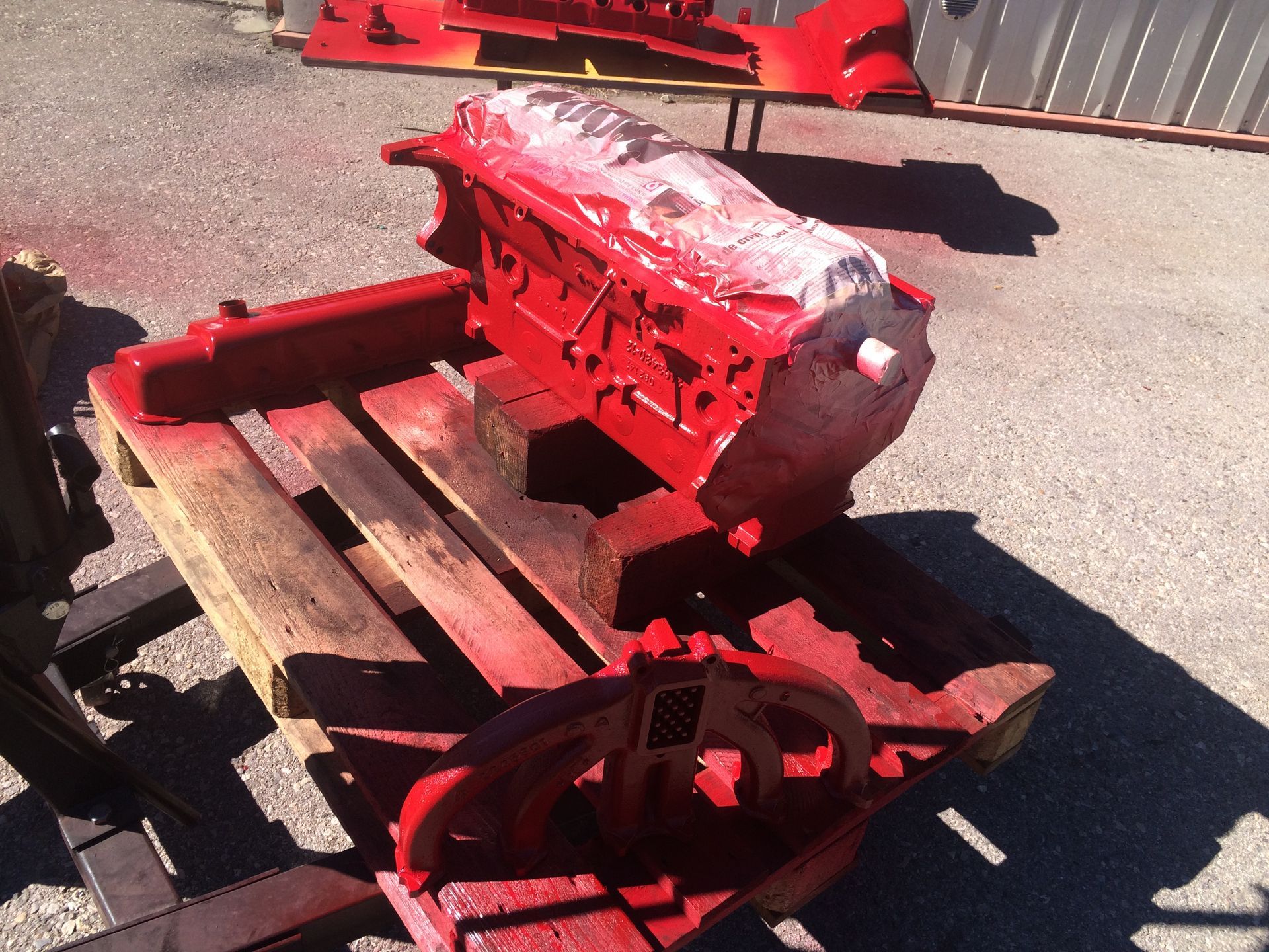 Un bloc moteur rouge est posé sur une palette en bois