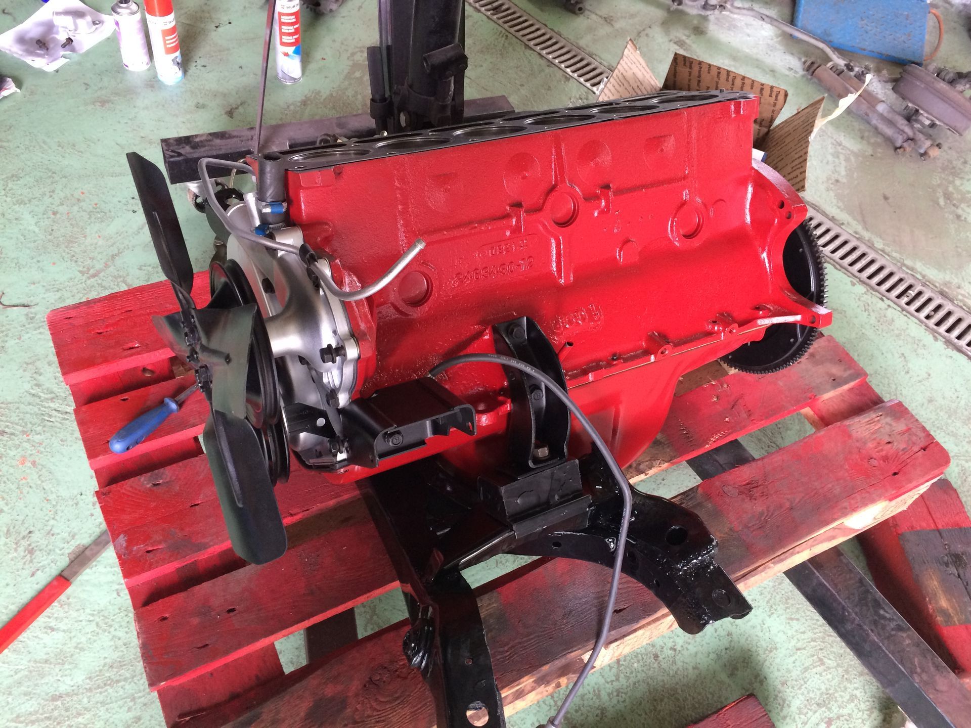 Un moteur rouge est posé sur une palette en bois