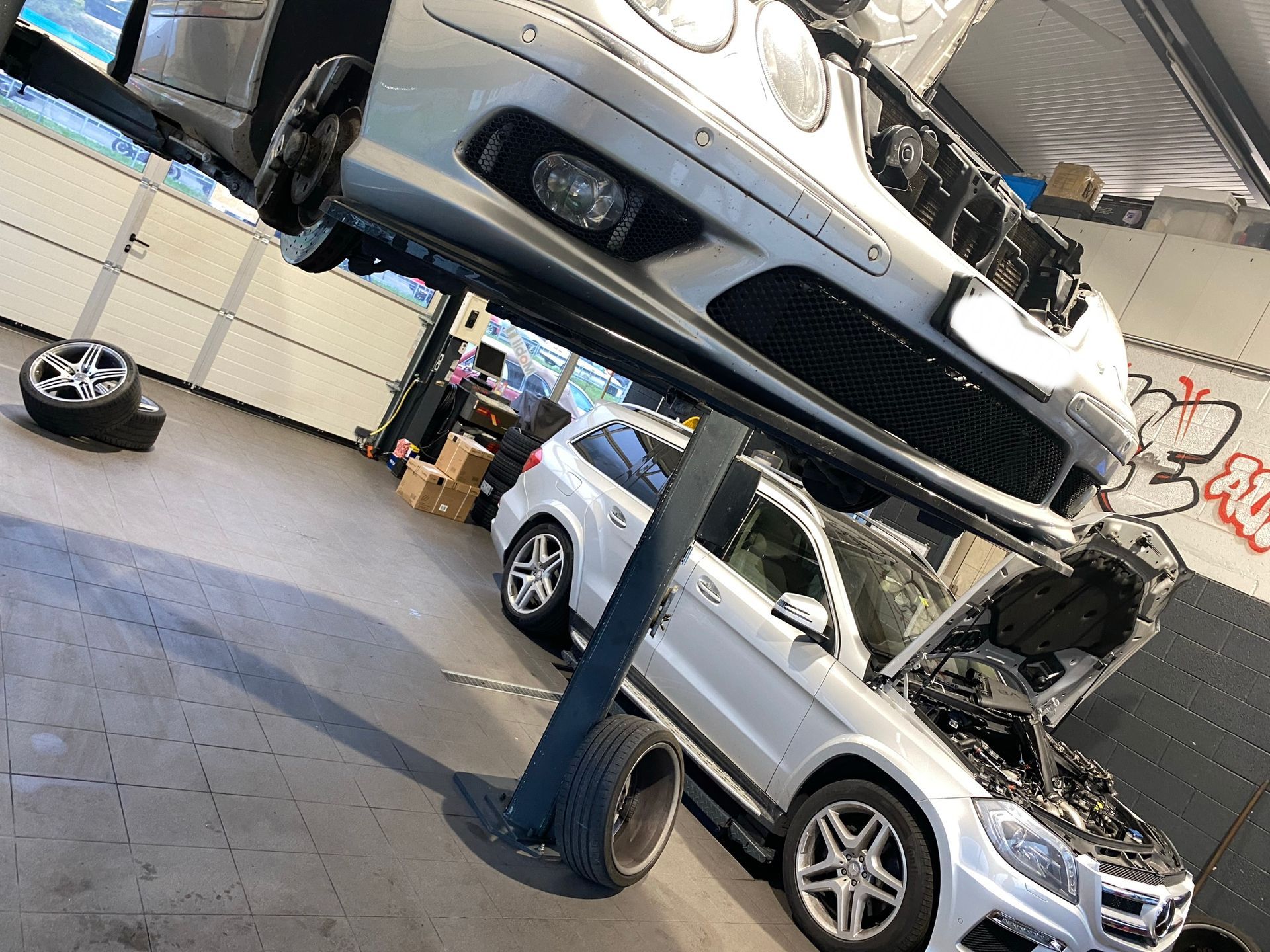 Deux voitures sont posées sur un ascenseur dans un garage.