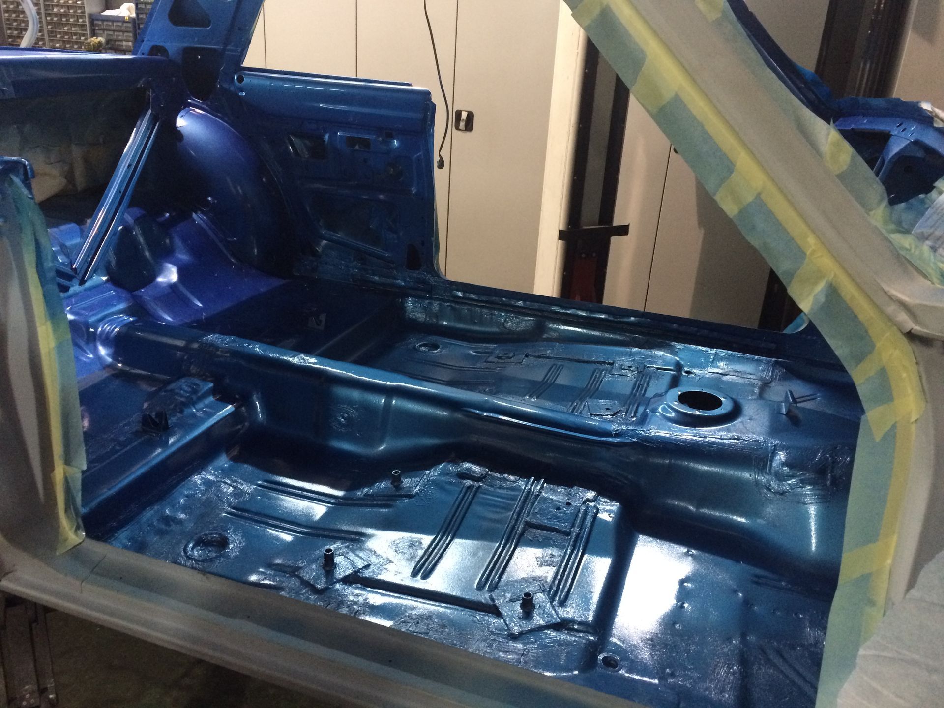 Une voiture bleue est peinte dans un garage