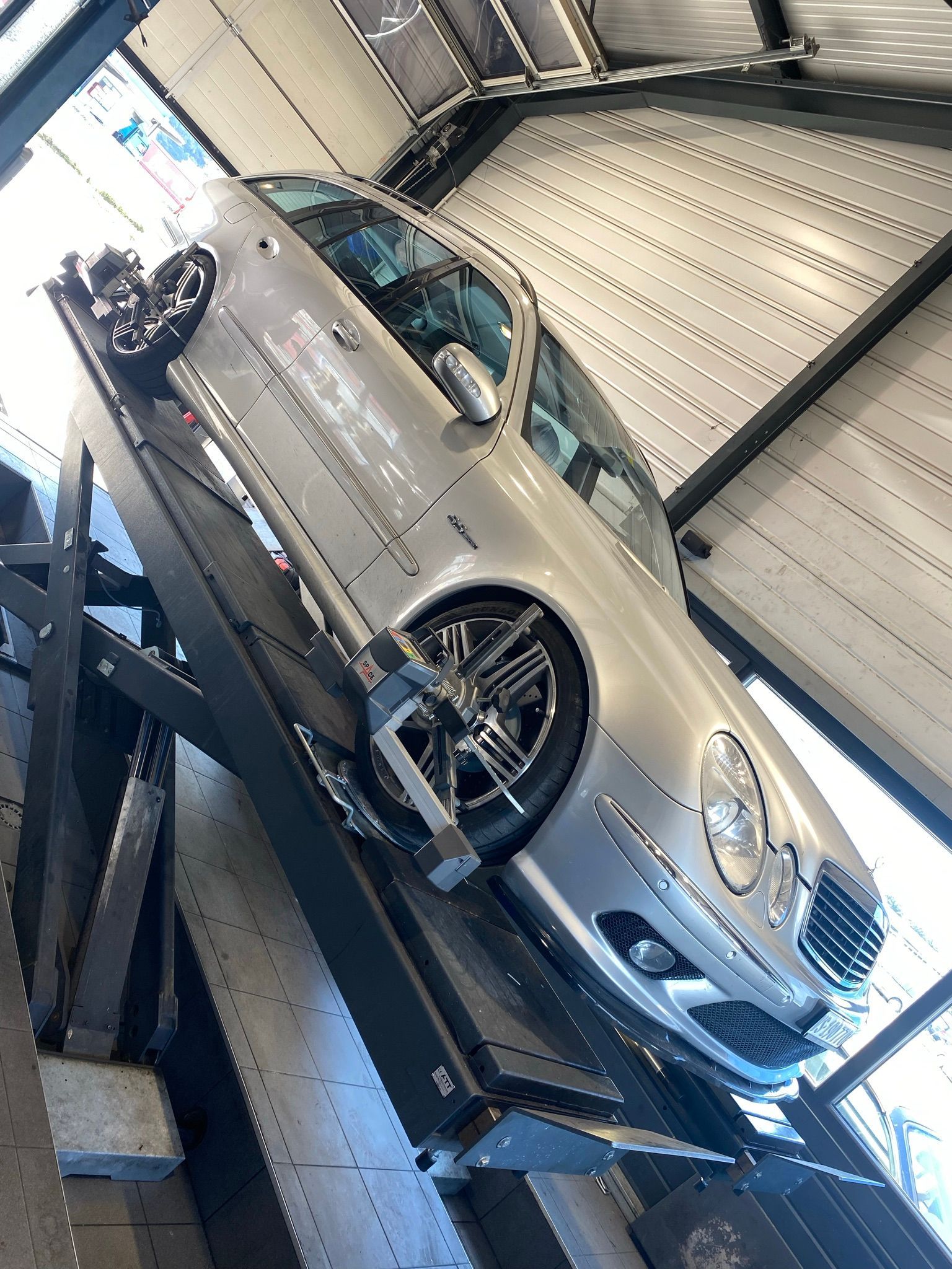 Une voiture argentée est assise sur un ascenseur dans un garage.