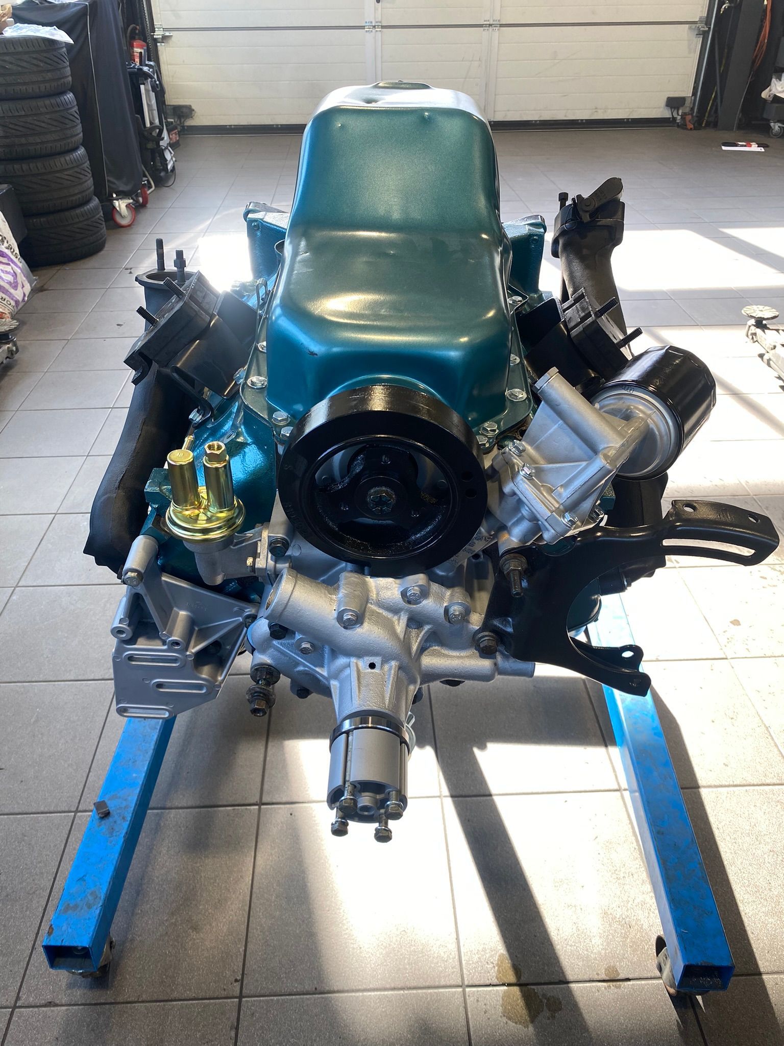 Un moteur de voiture est posé sur un support bleu dans un garage.