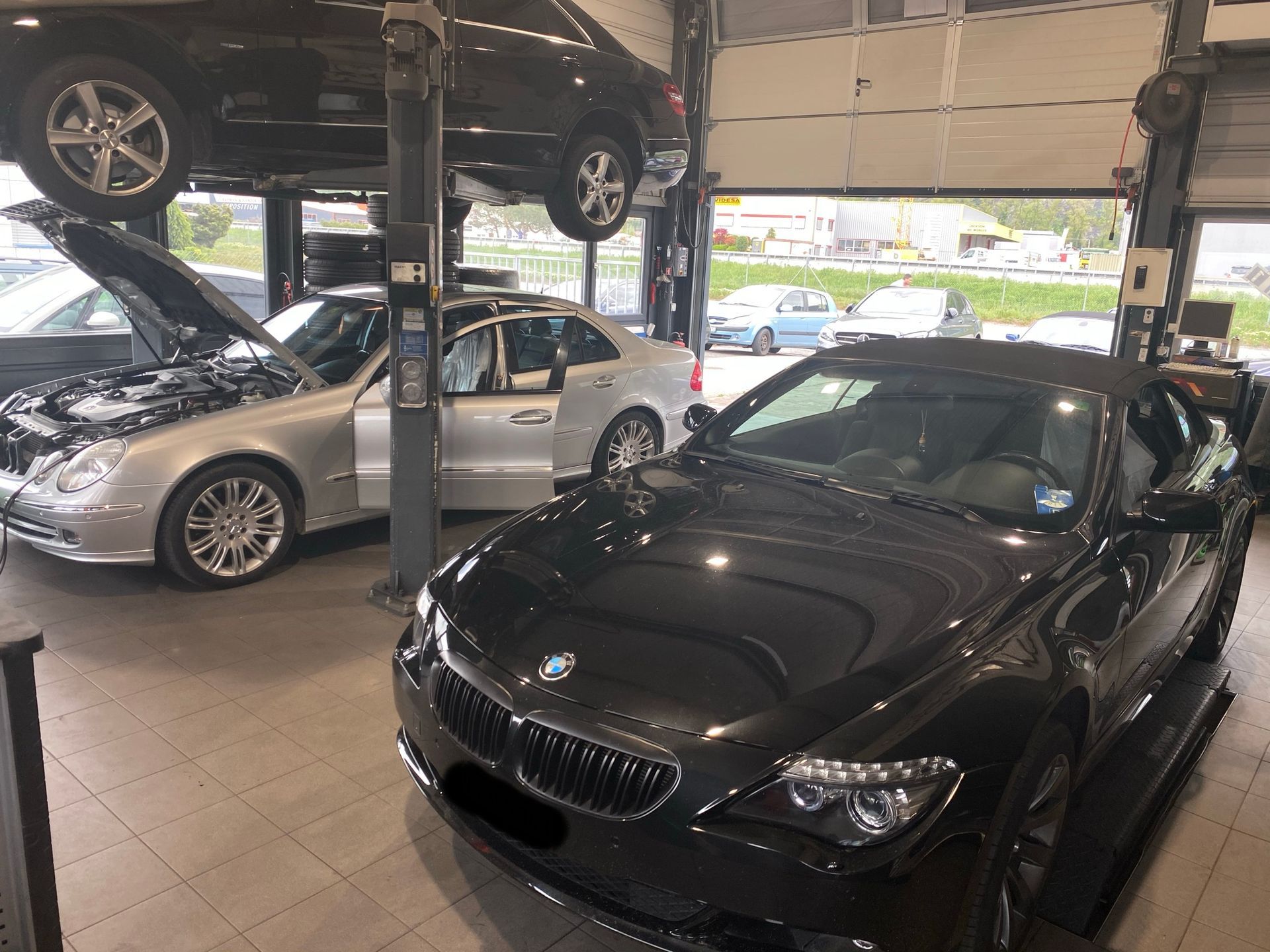 Deux voitures sont posées sur un ascenseur dans un garage.