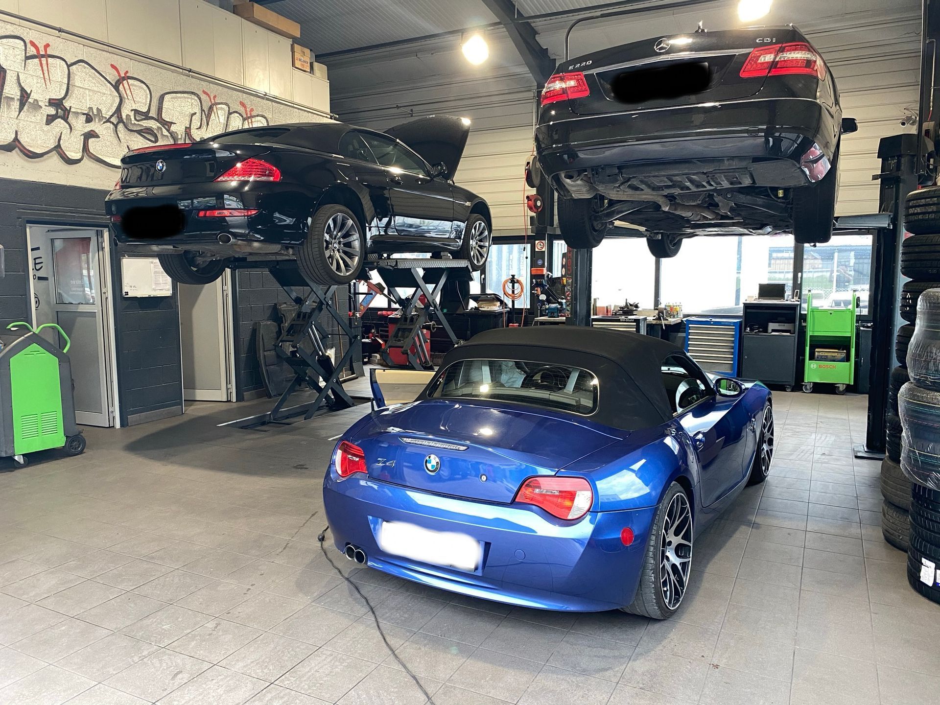 Une voiture bleue est garée dans un garage à côté d’une voiture noire.