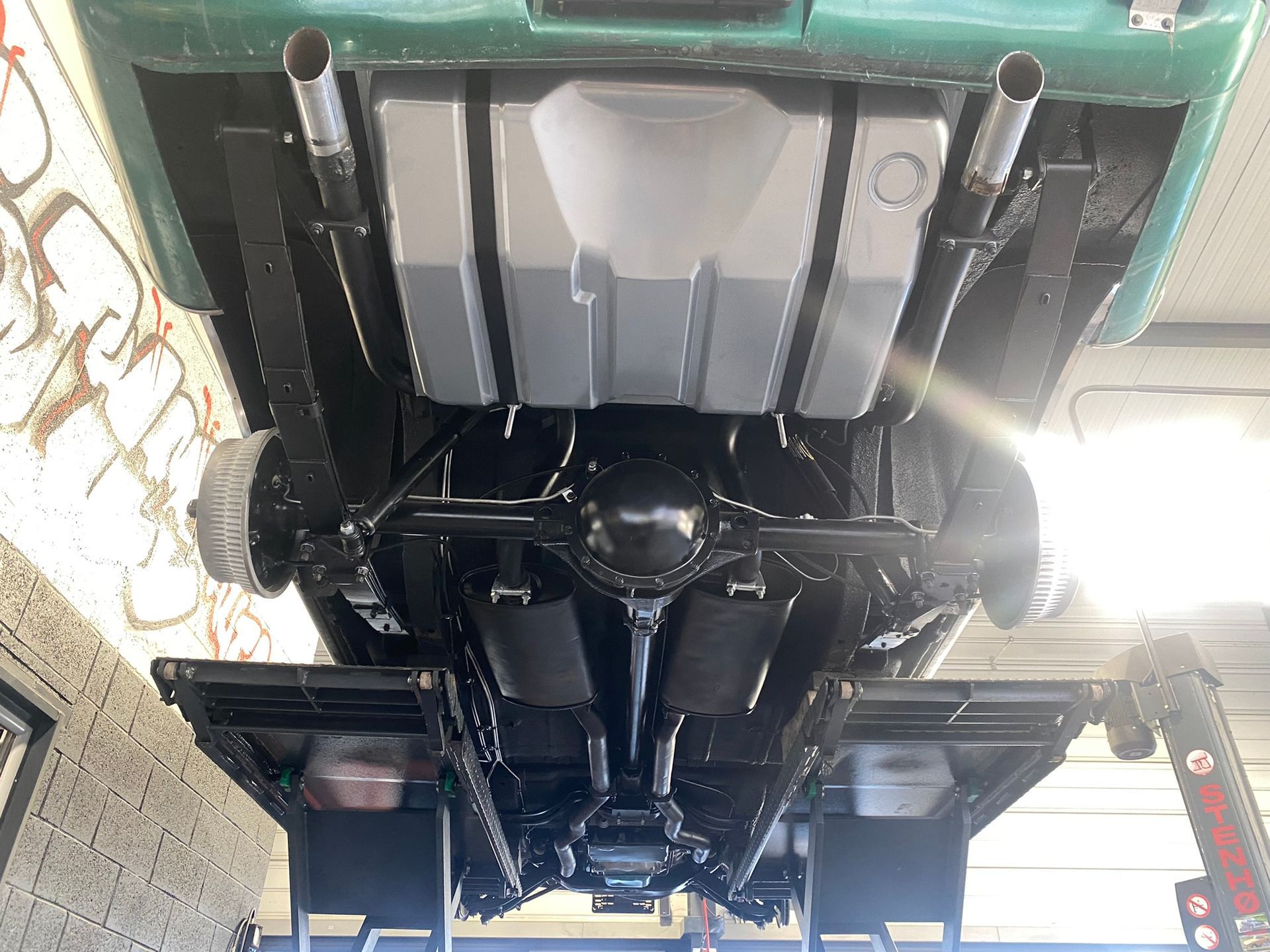 Le dessous d’une voiture repose sur un ascenseur dans un garage.