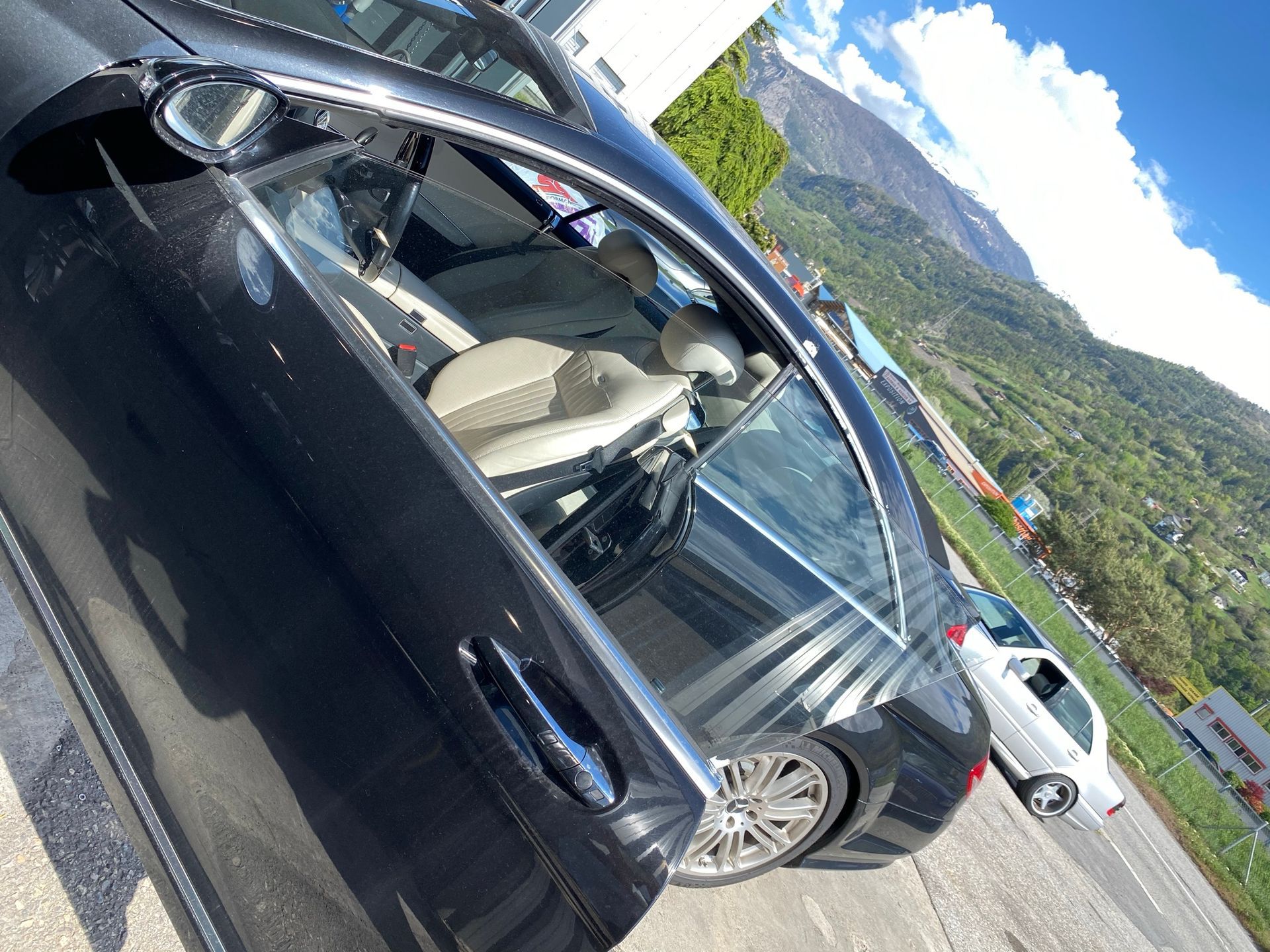 Une voiture noire avec la porte ouverte est garée sur le bord de la route.