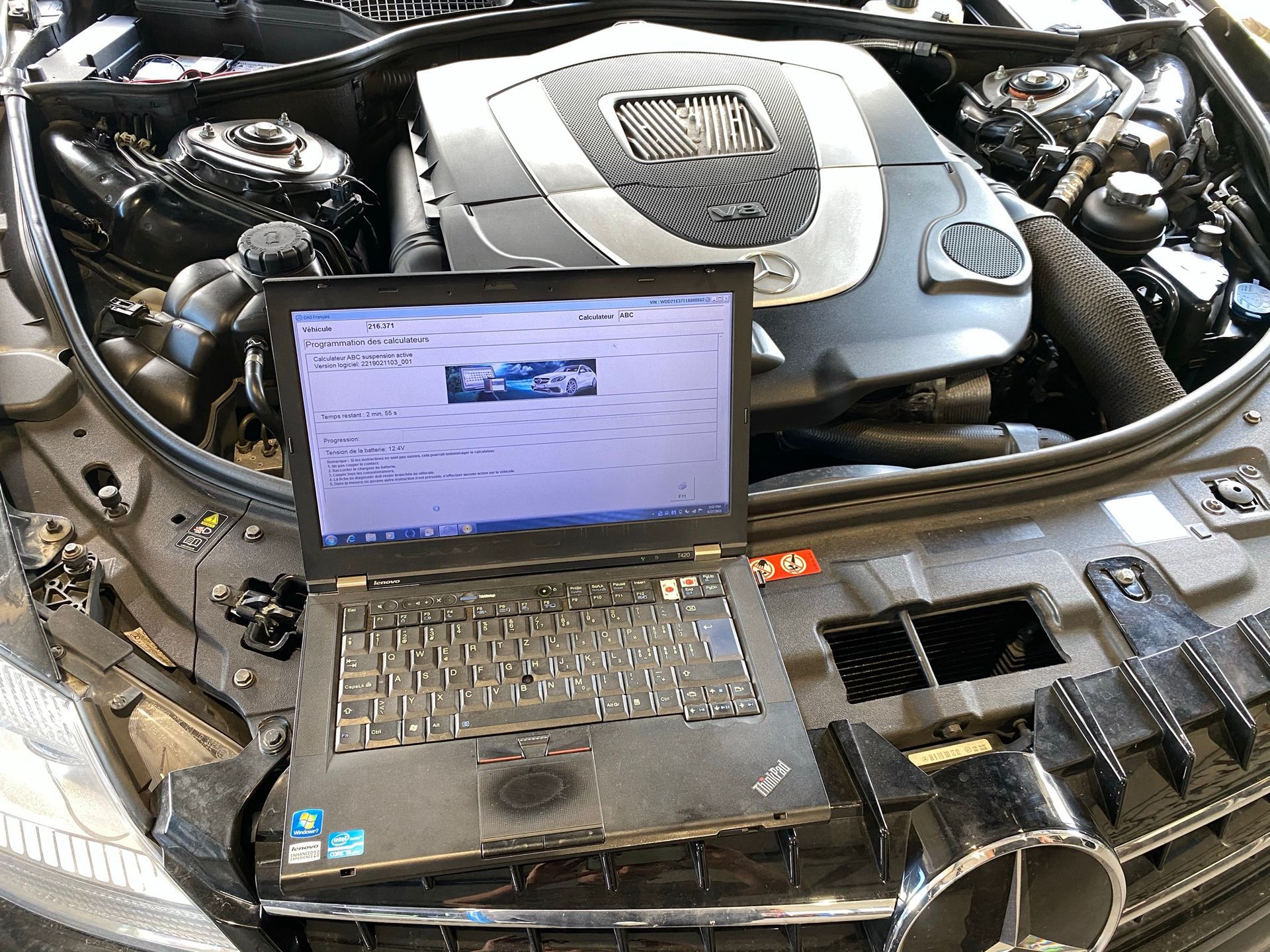 Un ordinateur portable se trouve sous le capot d’une voiture.