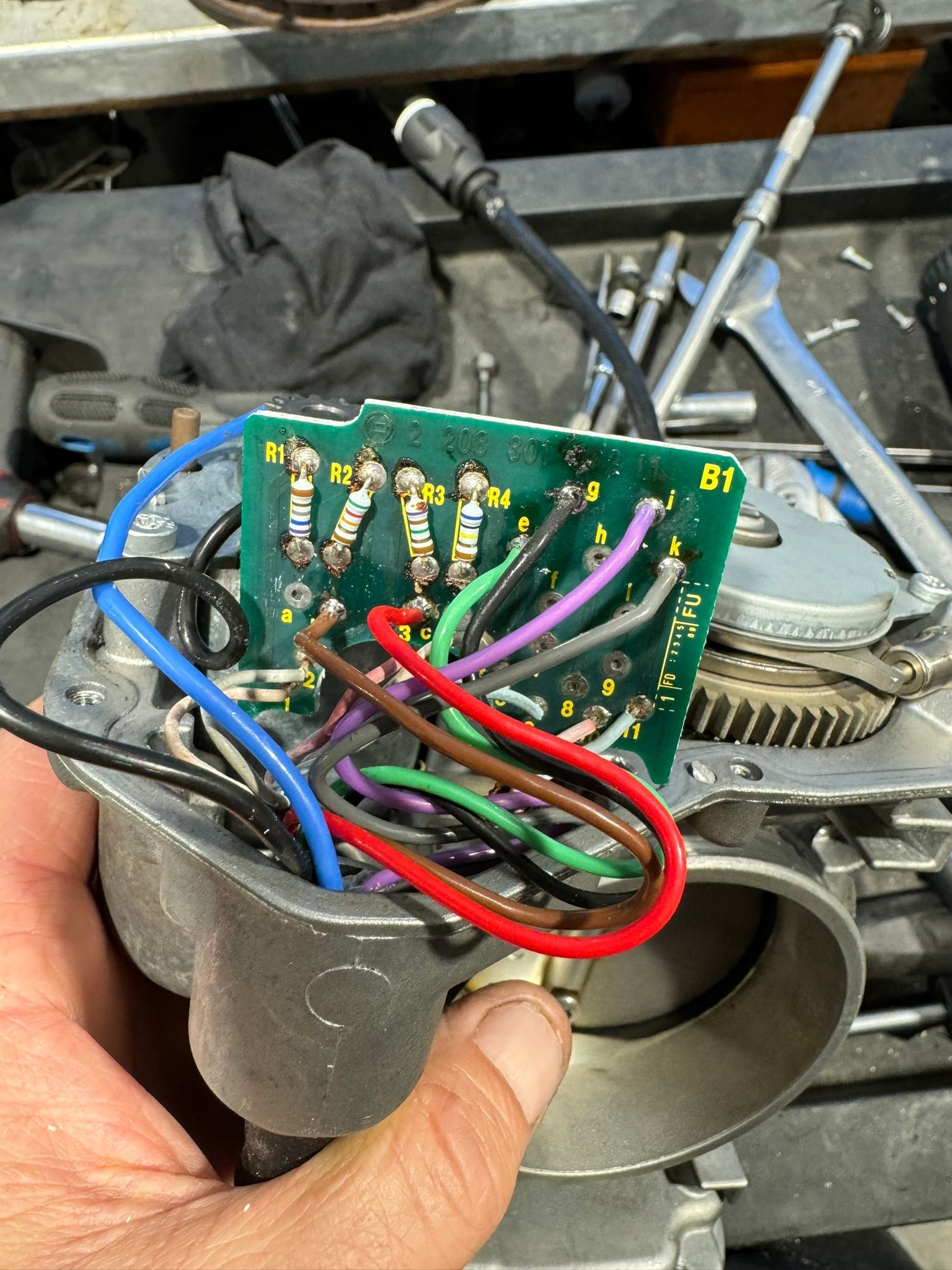 Une personne tient un circuit imprimé d’où sortent des fils.