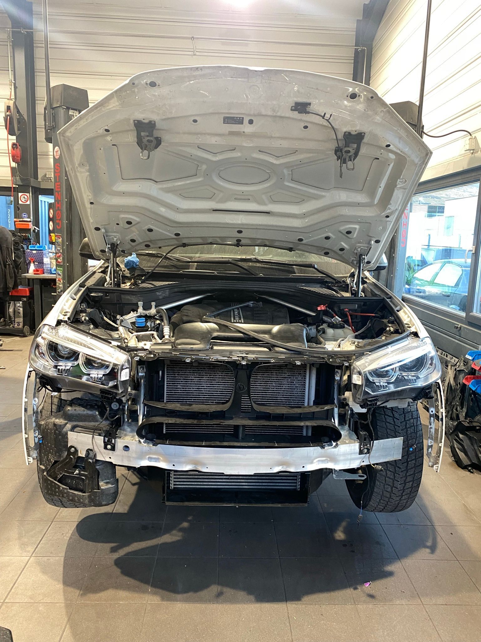 Un camion blanc avec le capot ouvert est assis dans un garage.