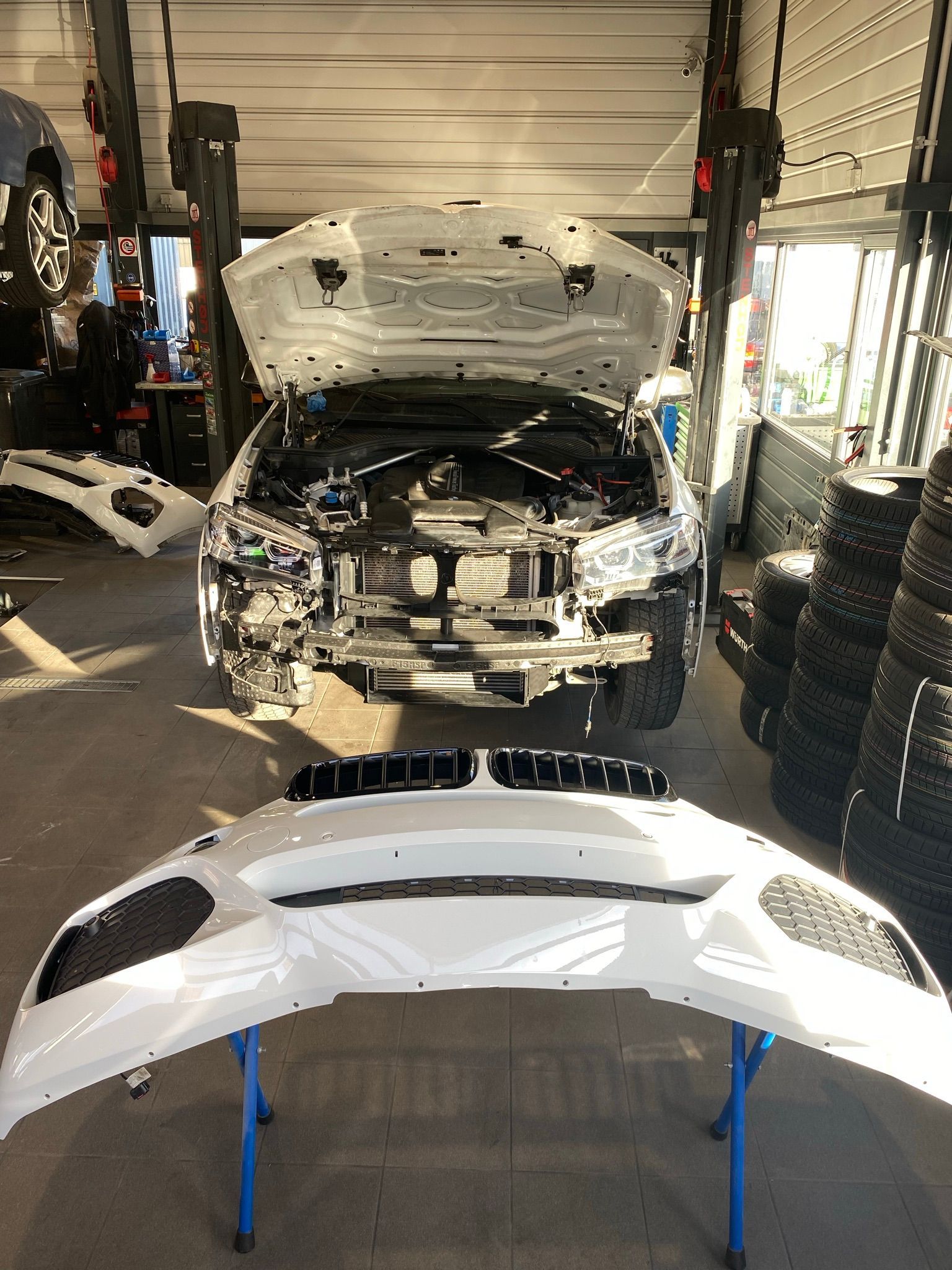 Une voiture avec le capot ouvert est posée sur une table dans un garage.