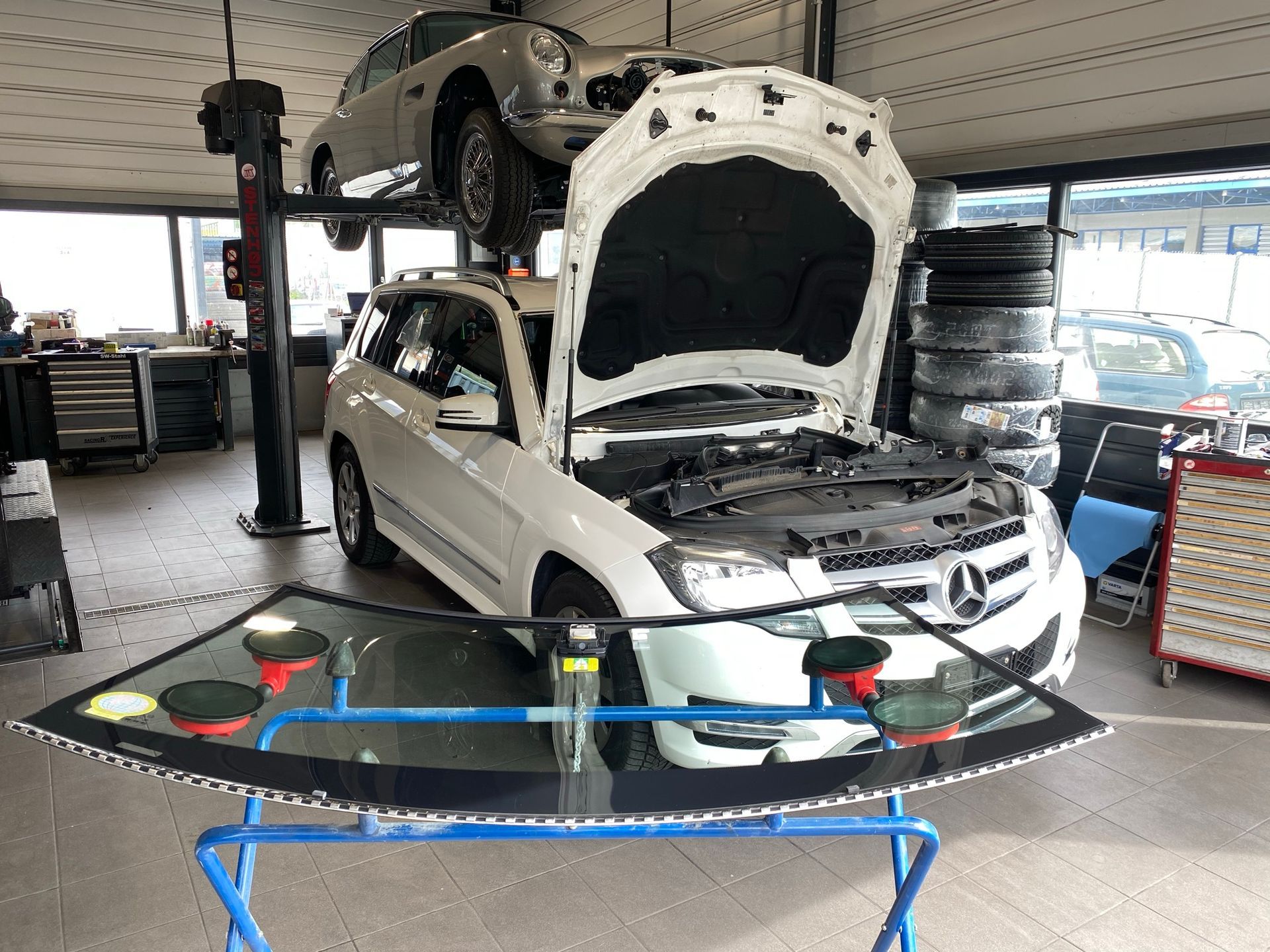 Une voiture blanche avec le capot ouvert est assise dans un garage.