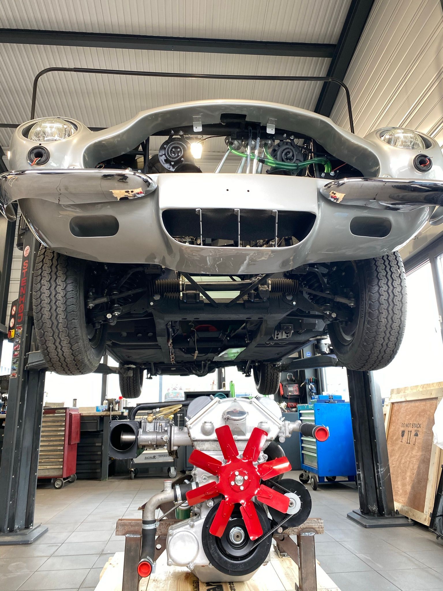 Une voiture est posée sur un ascenseur dans un garage avec le moteur exposé.