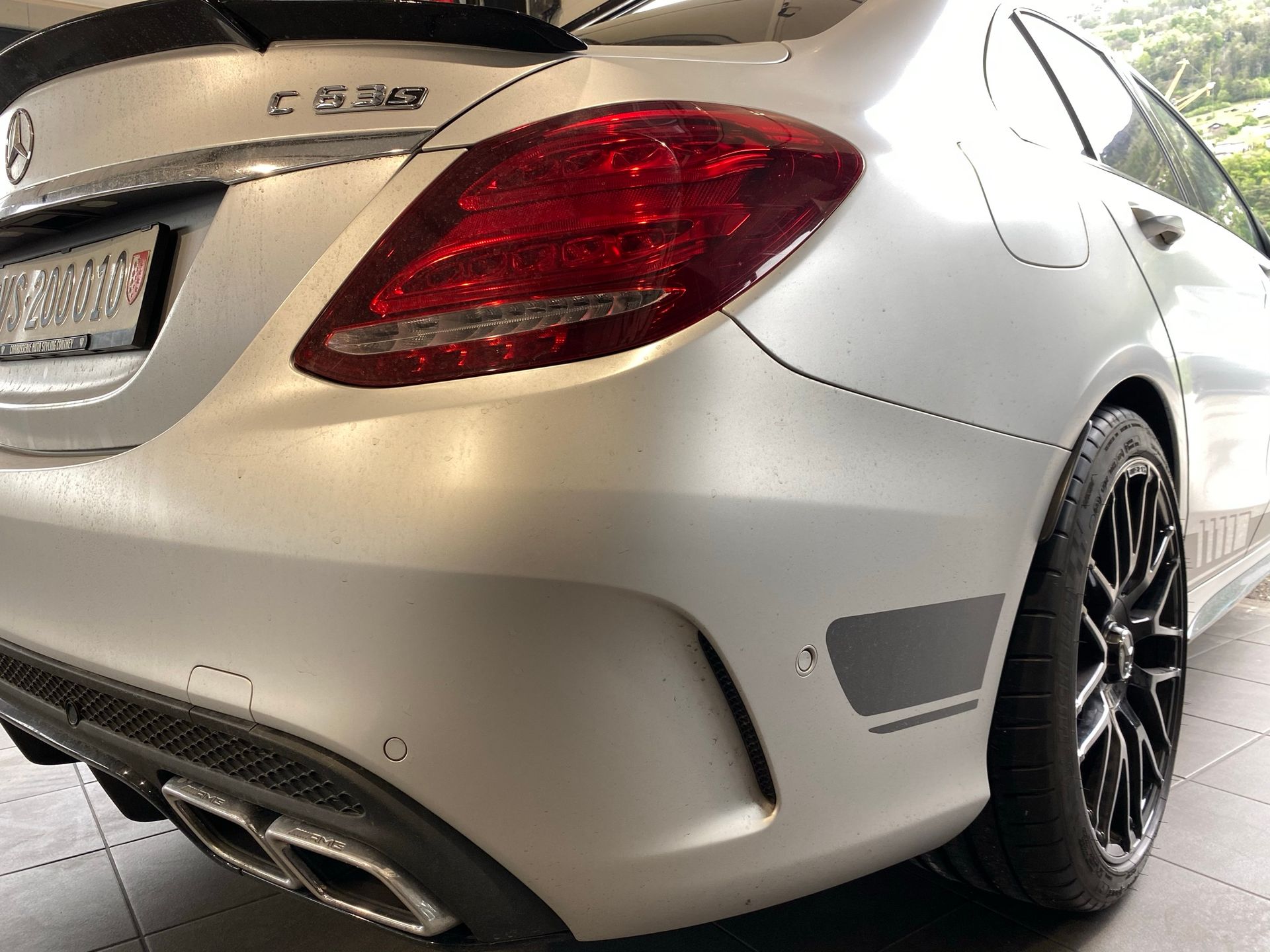 Une Mercedes Benz Classe C blanche est garée dans un garage.