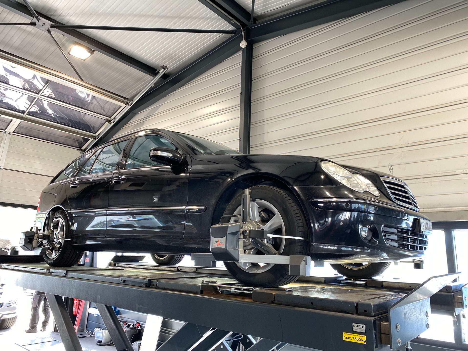 Une voiture noire est assise au sommet d’un ascenseur dans un garage.