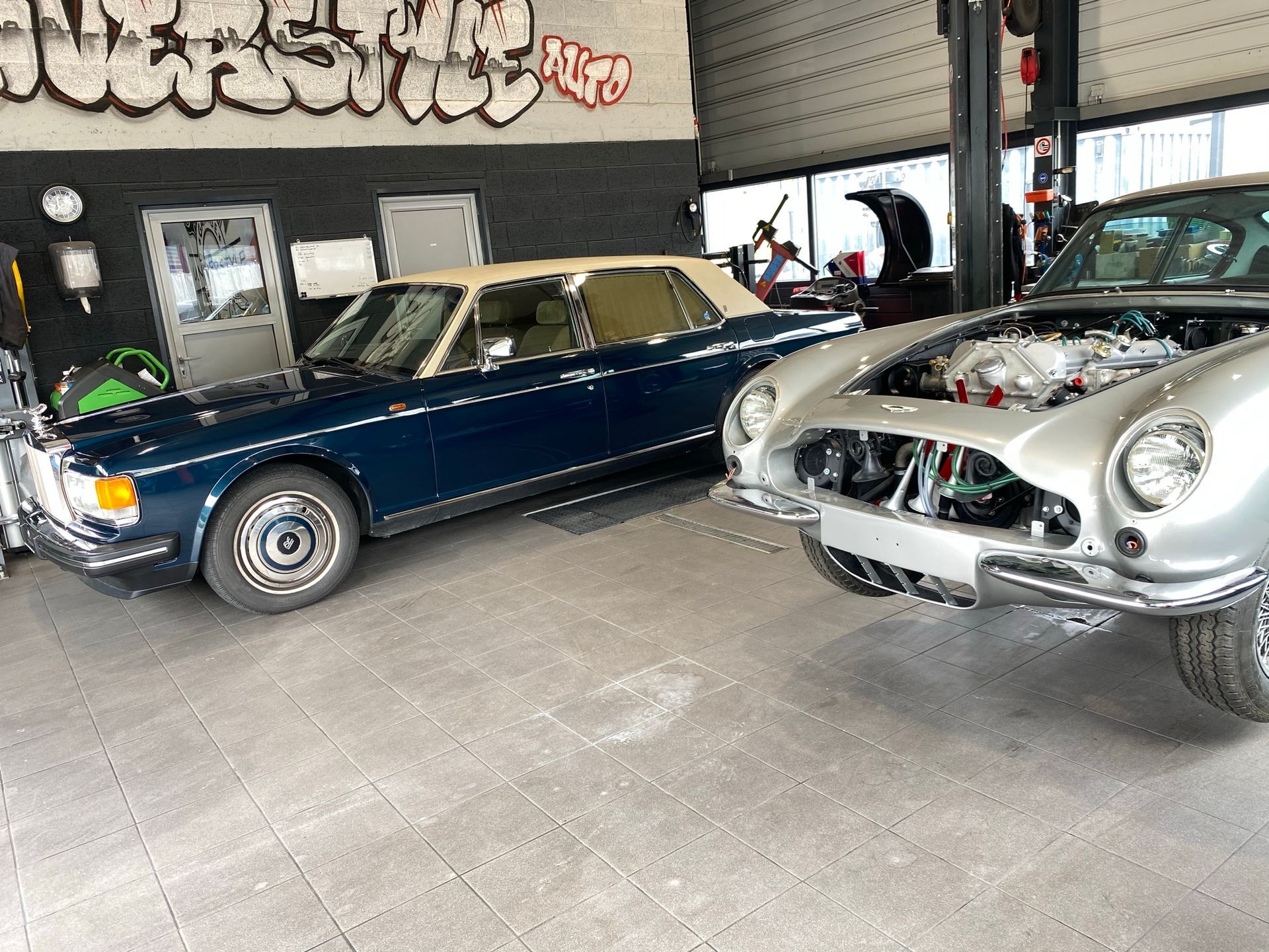 Deux voitures sont garées dans un garage avec des graffitis sur les murs.