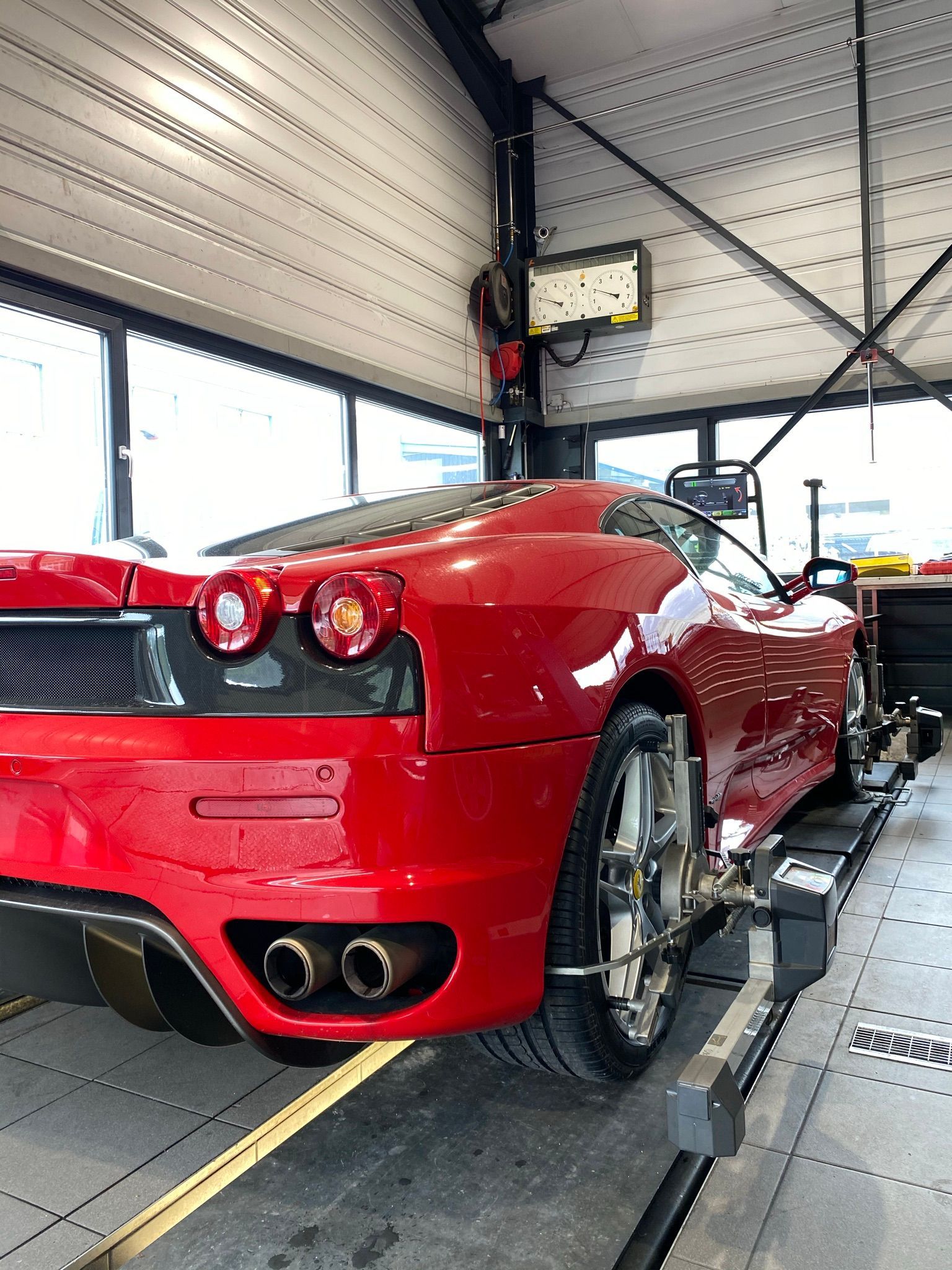 Une voiture de sport rouge est en train d'être alignée dans un garage.