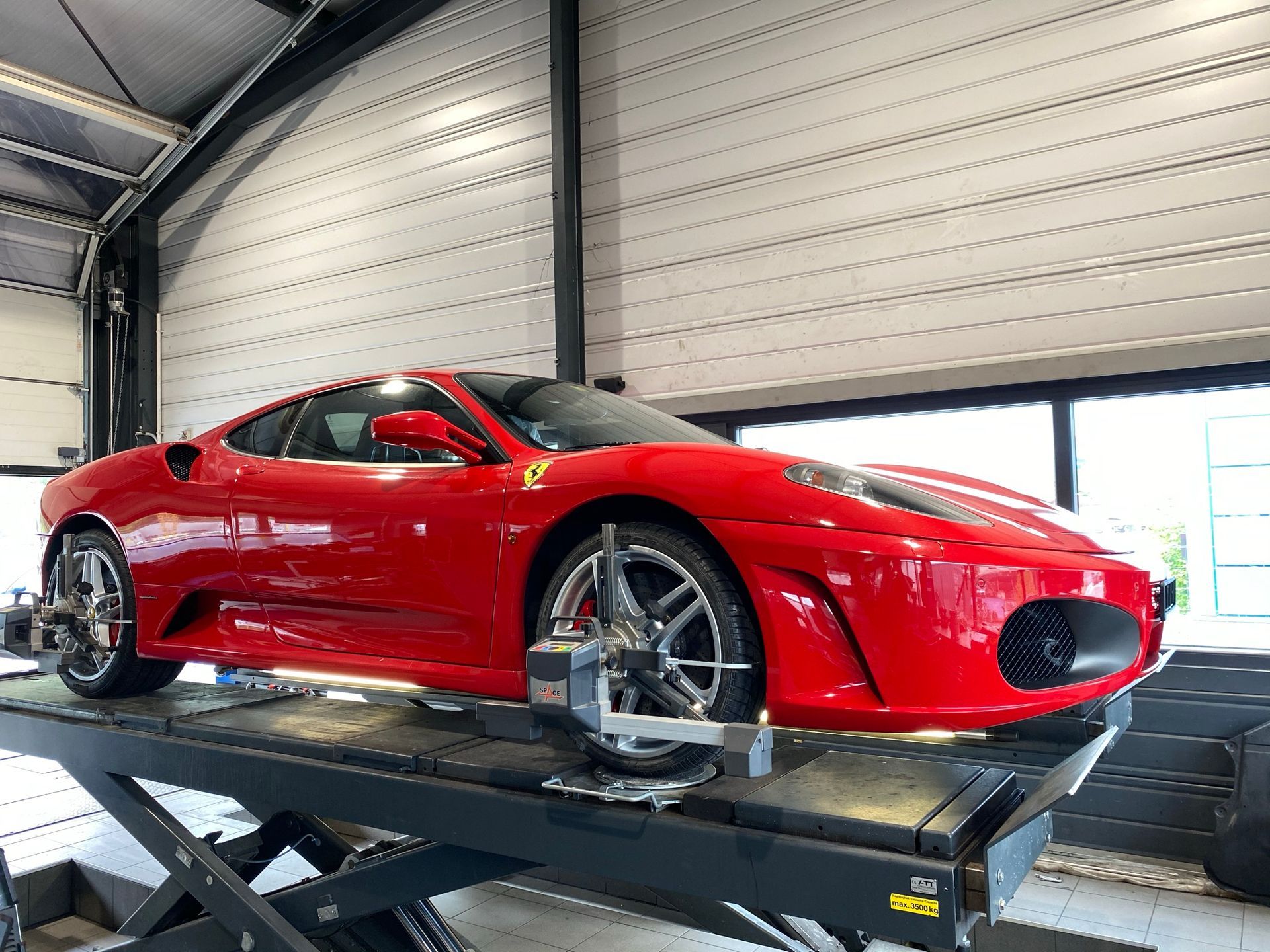 Une voiture de sport rouge est assise sur un ascenseur dans un garage.