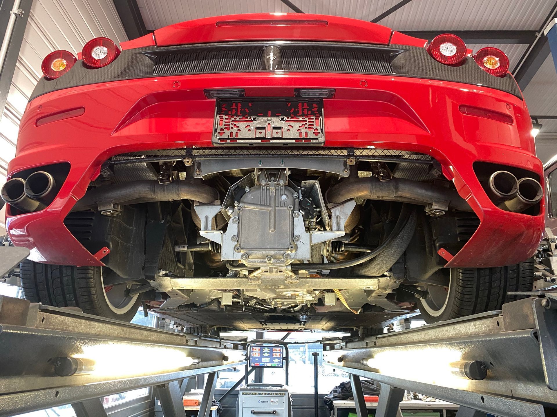 Une Ferrari rouge est assise sur un ascenseur dans un garage.