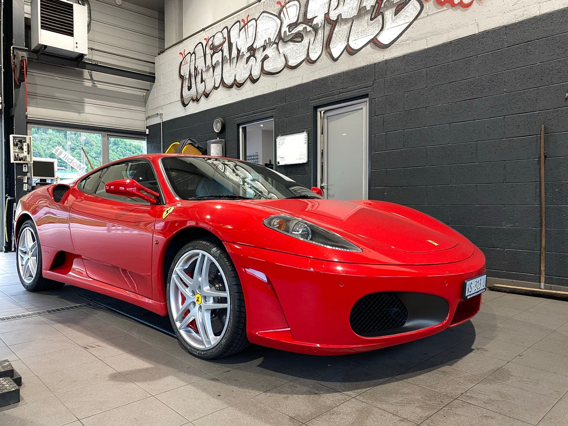 Une voiture de sport Ferrari rouge est garée dans un garage.