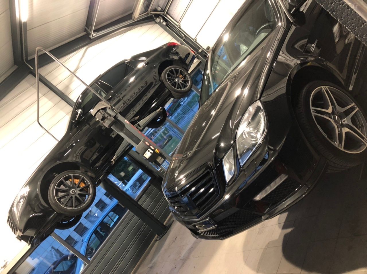 Mercedes-Benz noire suspendue sur un pont élévateur pendant un entretien technique dans le garage Universtyle Sion