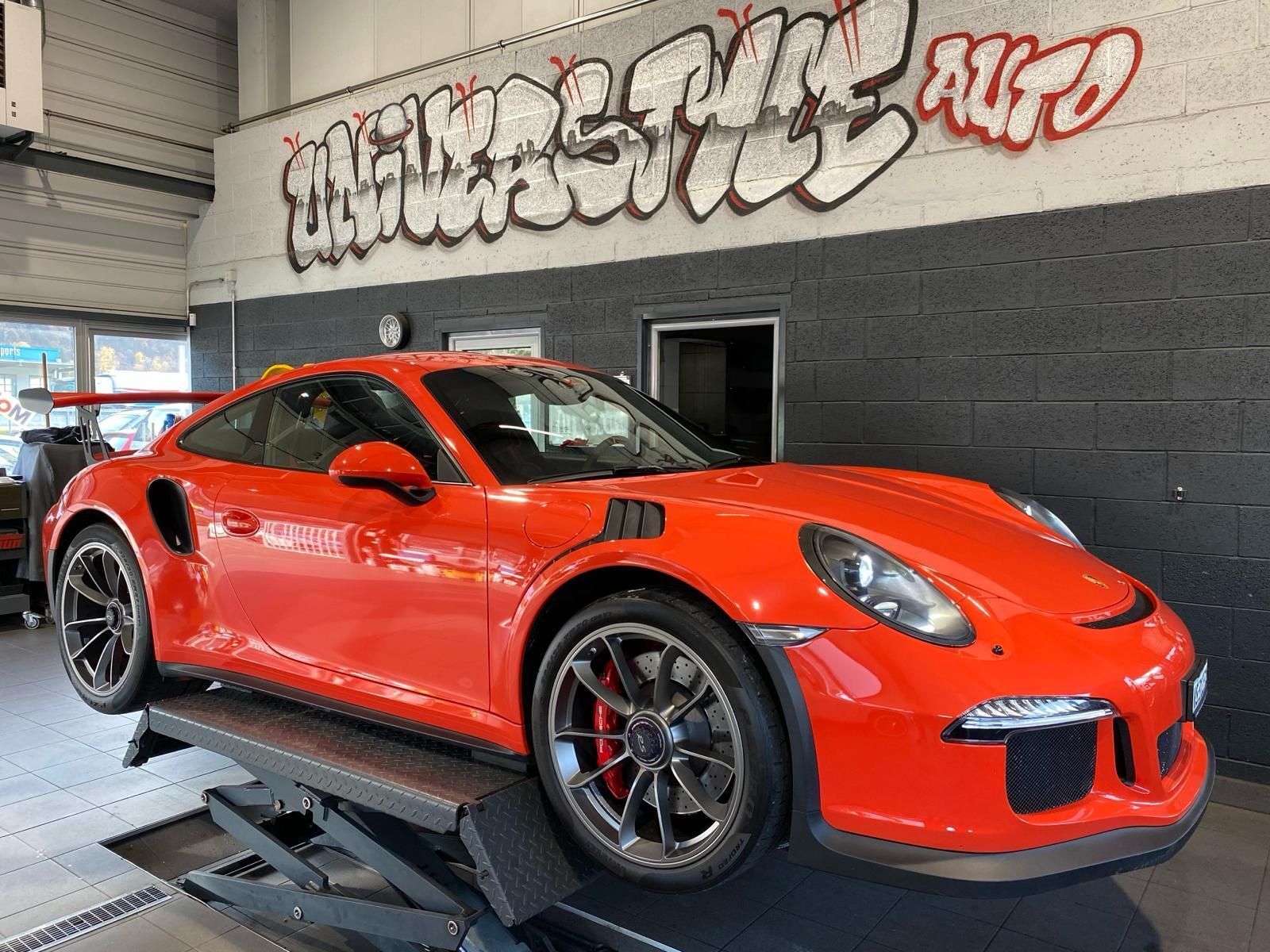 Porsche rouge sportive sur élévateur dans l'atelier de Garage Universtyle Sion prête pour l'entretien