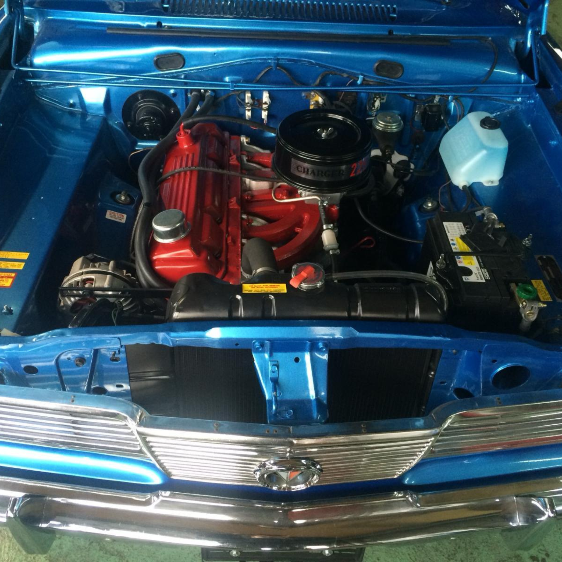 Une voiture bleue avec le capot ouvert a un moteur rouge