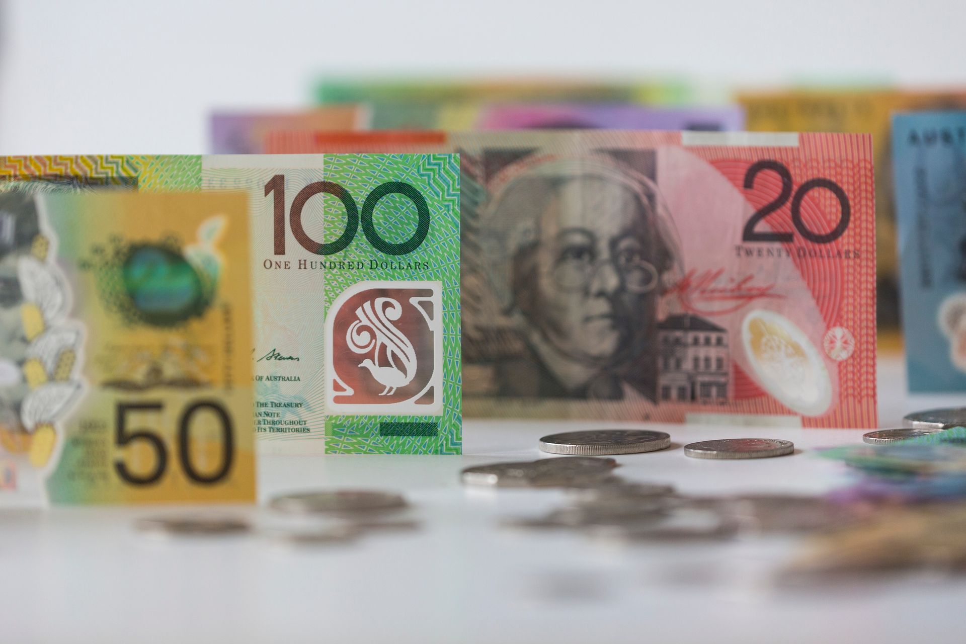Australian banknotes and coins arranged on a white surface, showing various denominations.