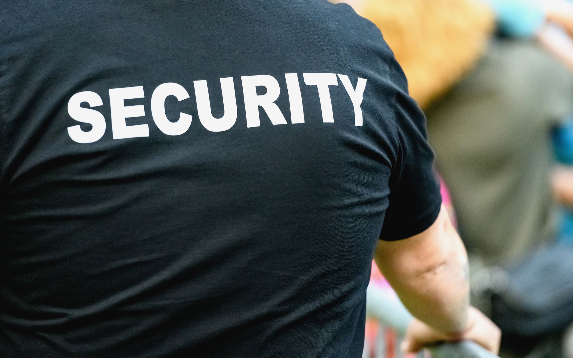 Back of a security guard in a black shirt with 