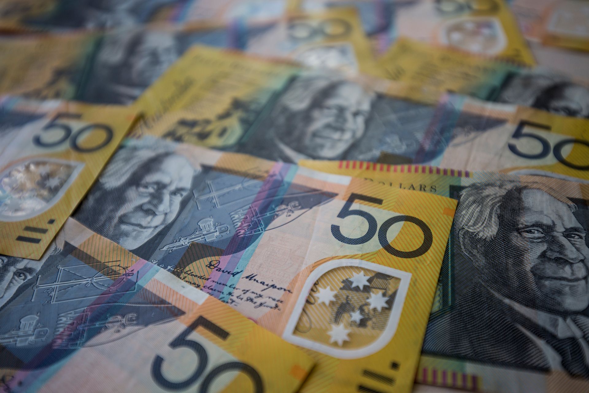Pile of Australian $50 banknotes, featuring portraits and the Australian map.