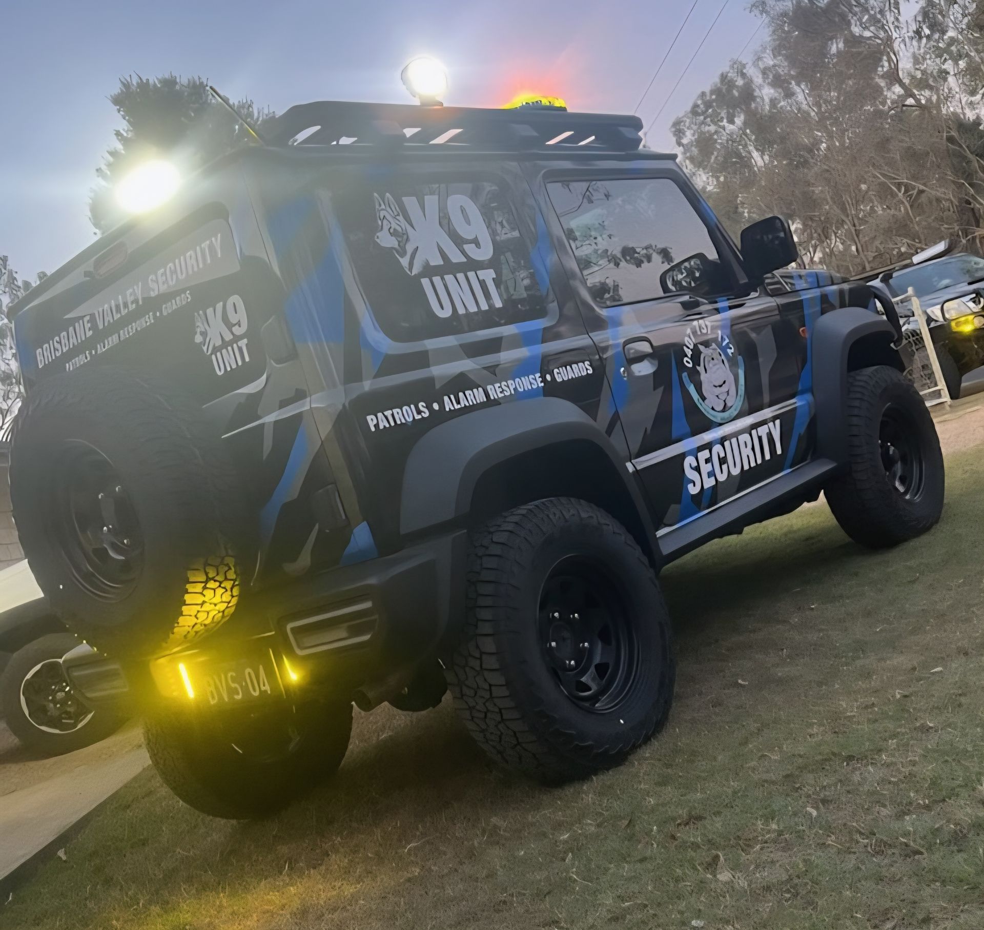 Police car with flashing red and blue lights on roof. Blue and white checkered pattern along side.