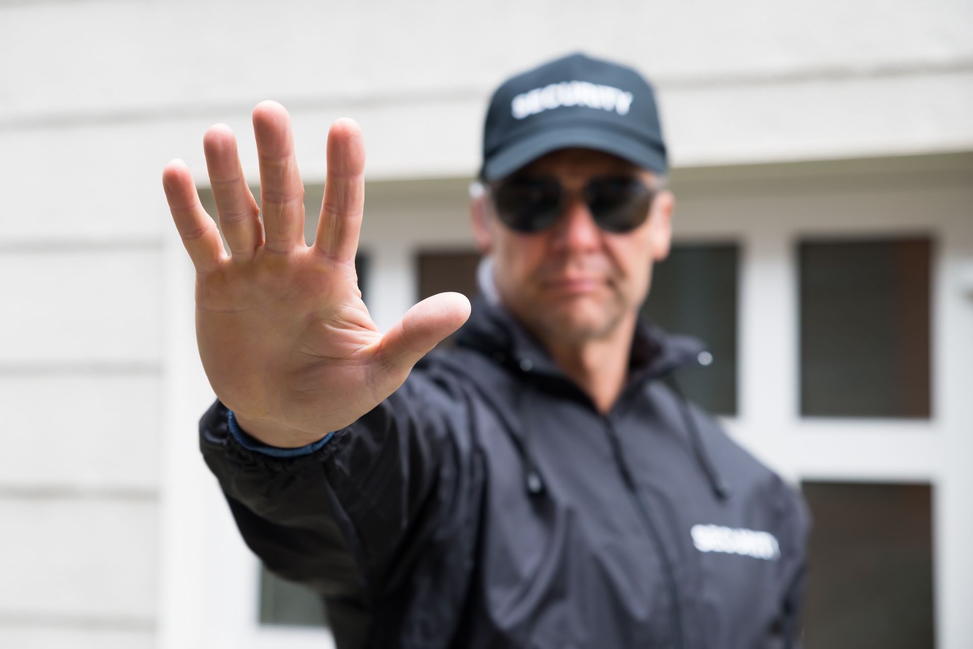 Security guard standing in front of a gate; light blue shirt with 