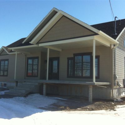 Maison beige avec porche; neige au sol.