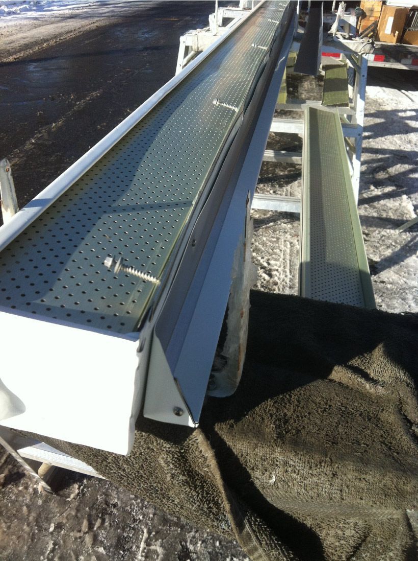 Machine à gouttière blanche en aluminium perforé, posée sur béton.