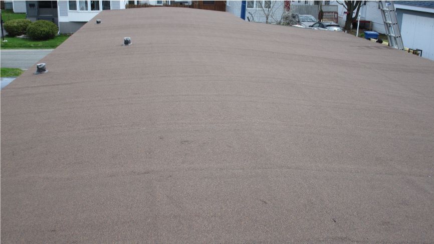 Toit plat et brun d'un bâtiment avec des évents argentés, à l'extérieur.