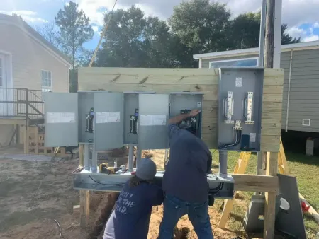 Two men are working on a electrical box in front of a house.