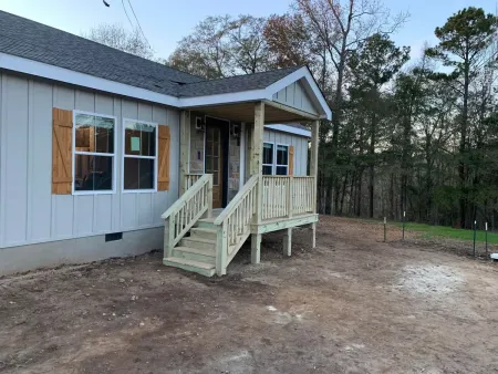 A mobile home with a porch and stairs in front of it.