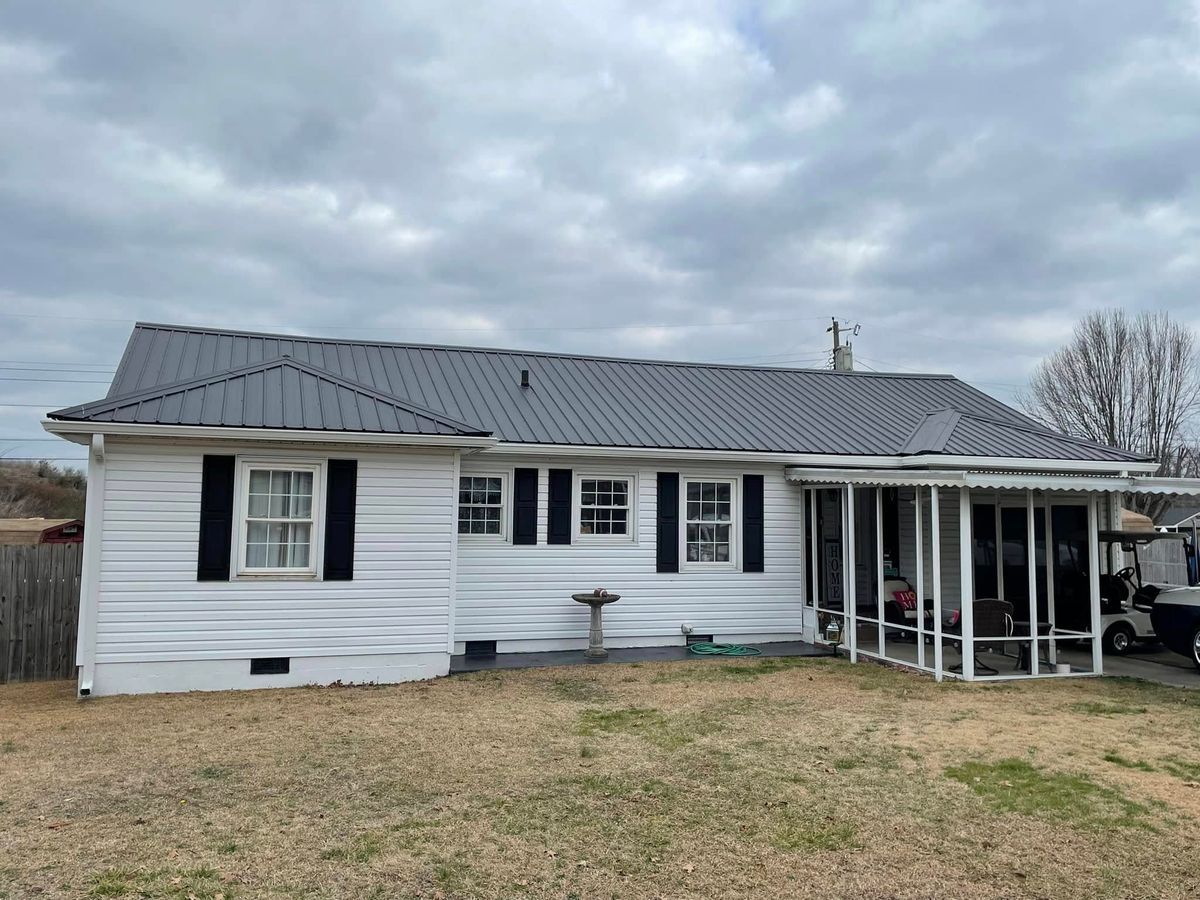 A white house with a metal roof and a porch.