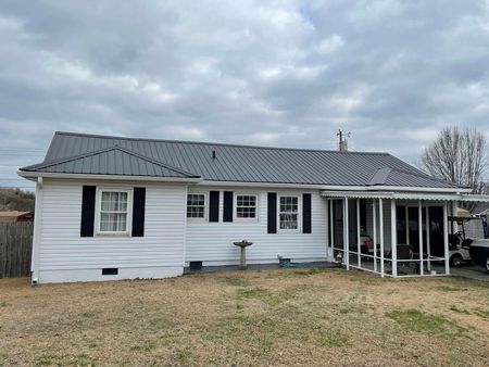 A white house with a metal roof and a porch.