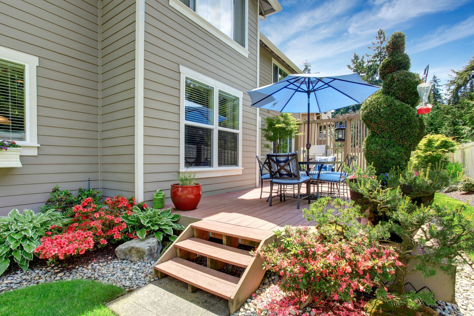 There is a patio with a table and chairs and an umbrella in the backyard of a house.