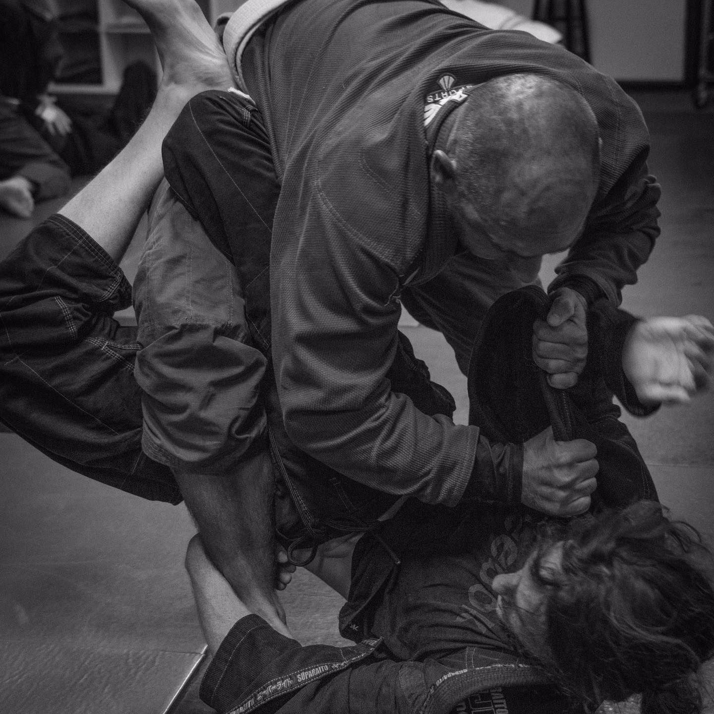 a black and white photo of two men wrestling with one wearing a shirt that says jiu-jitsu