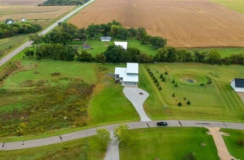 An aerial view of a house surrounded by fields and trees.