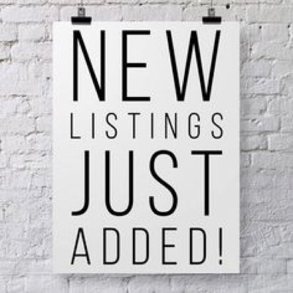 A sign that says new listings just added hangs on a white brick wall