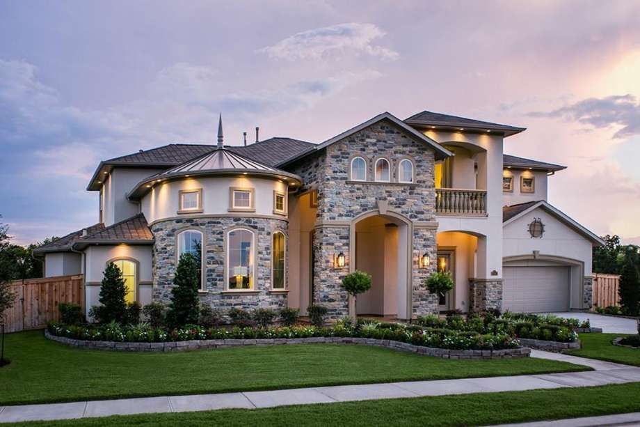 A large house with a lot of windows is sitting on top of a lush green lawn.