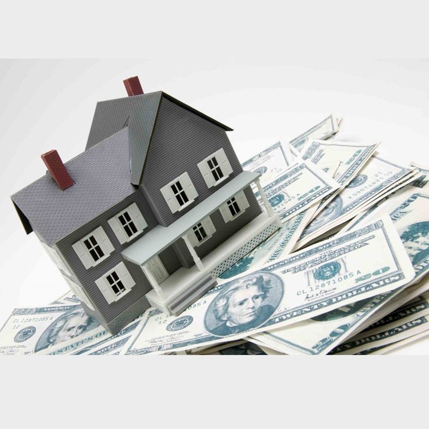 A model house is sitting on top of a pile of money