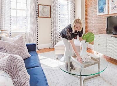 A woman is cleaning a coffee table in a living room.
