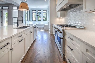 A kitchen with white cabinets , stainless steel appliances , and hardwood floors.