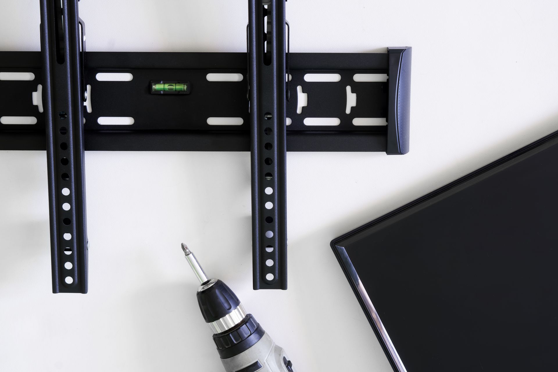 A drill is sitting on a table next to a tv mount.