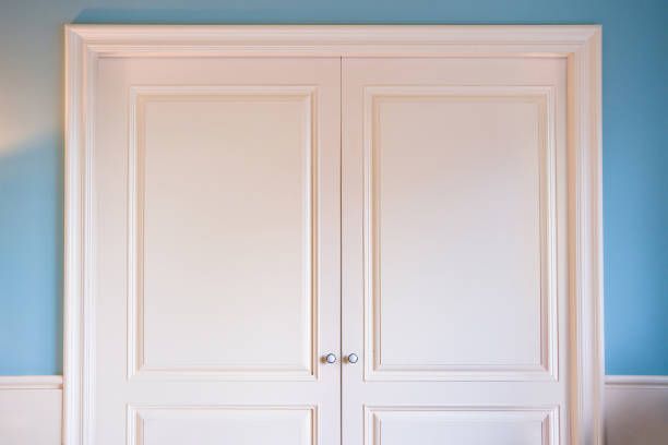 A pair of white doors with blue walls in a room.