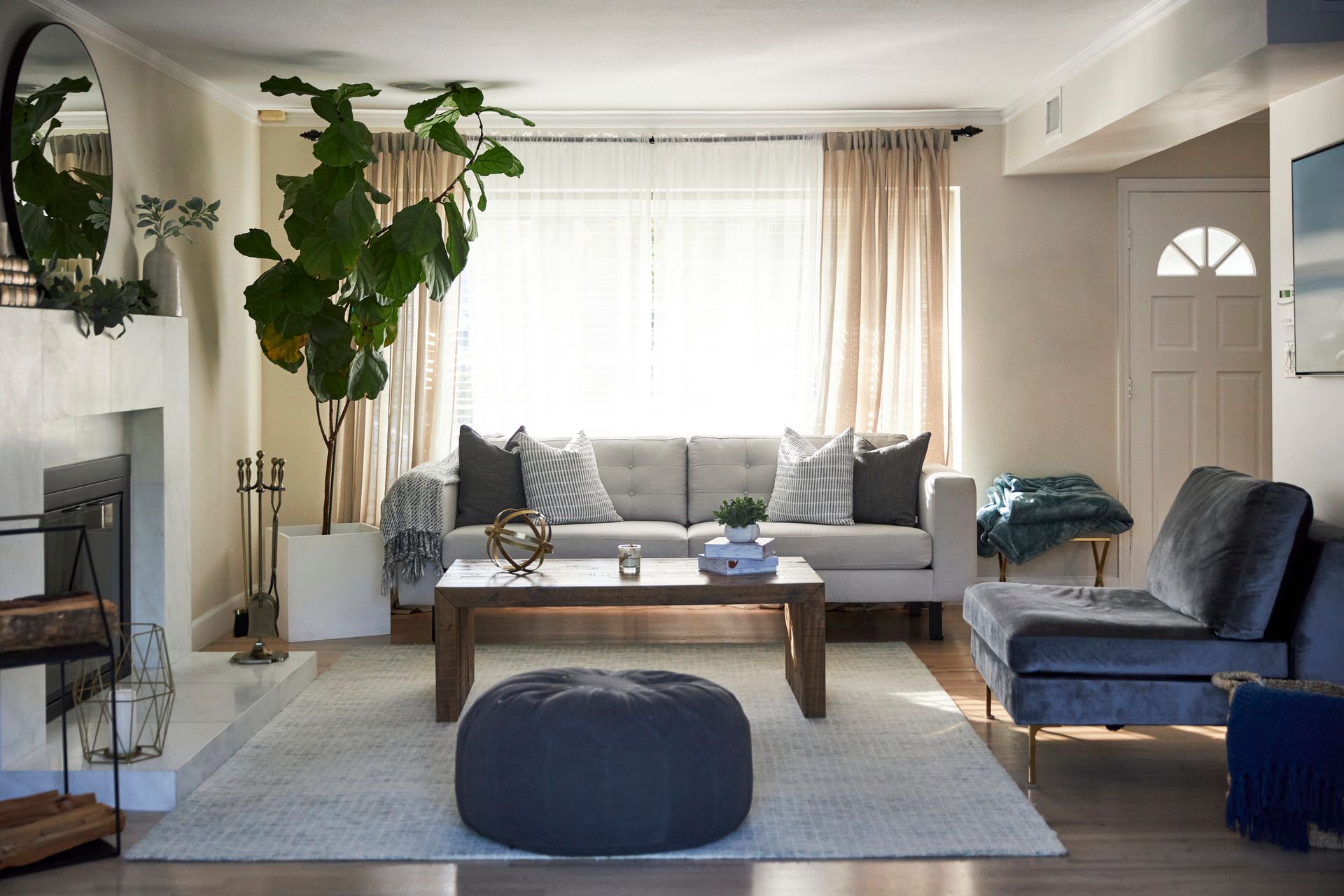 A living room with a couch , chairs , coffee table and ottoman.